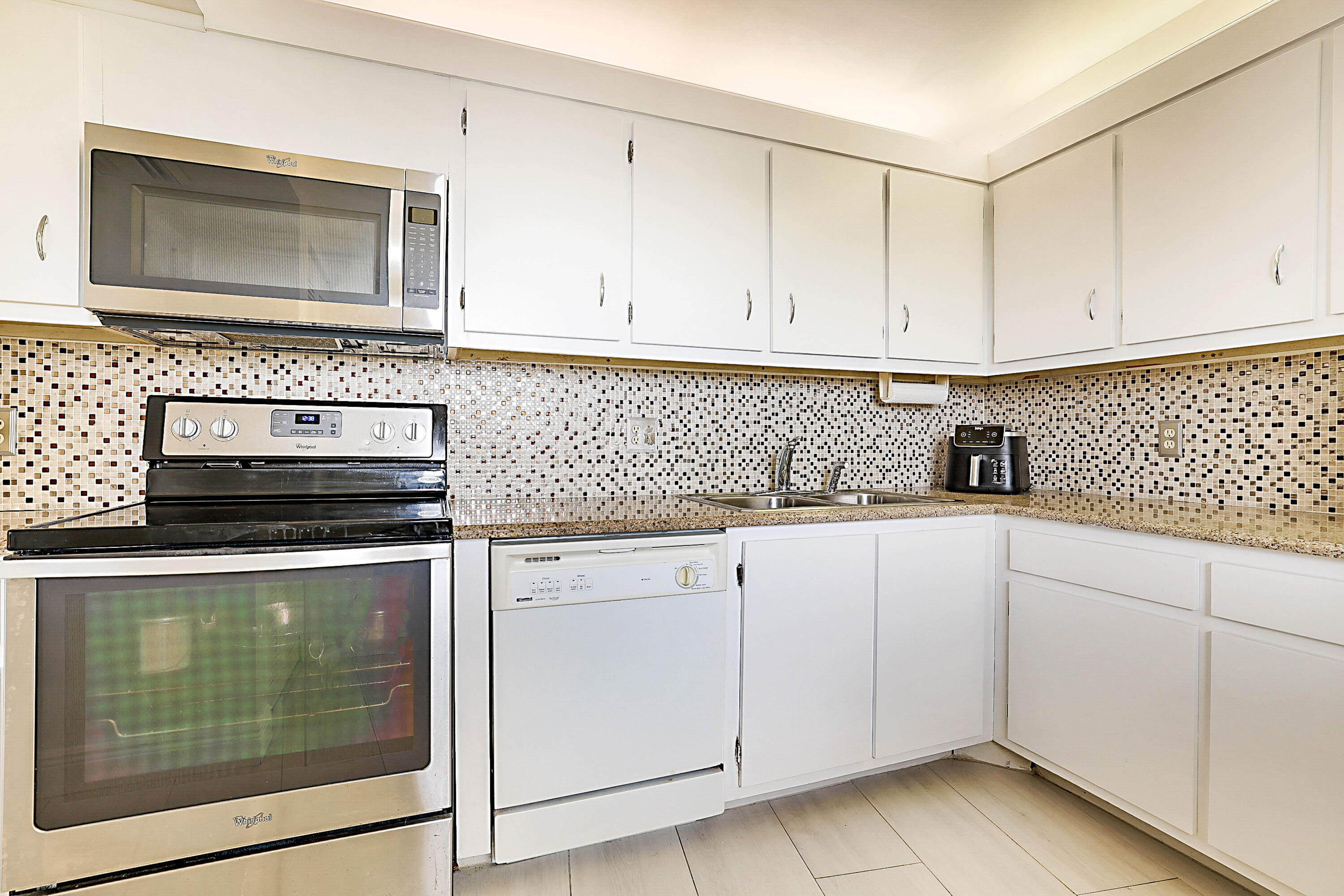 100 Ocean Trail Way, Unit 1003 Jupiter, FL 33477 - Photo 11 of 33 a kitchen with granite countertop white cabinets and stainless steel appliances