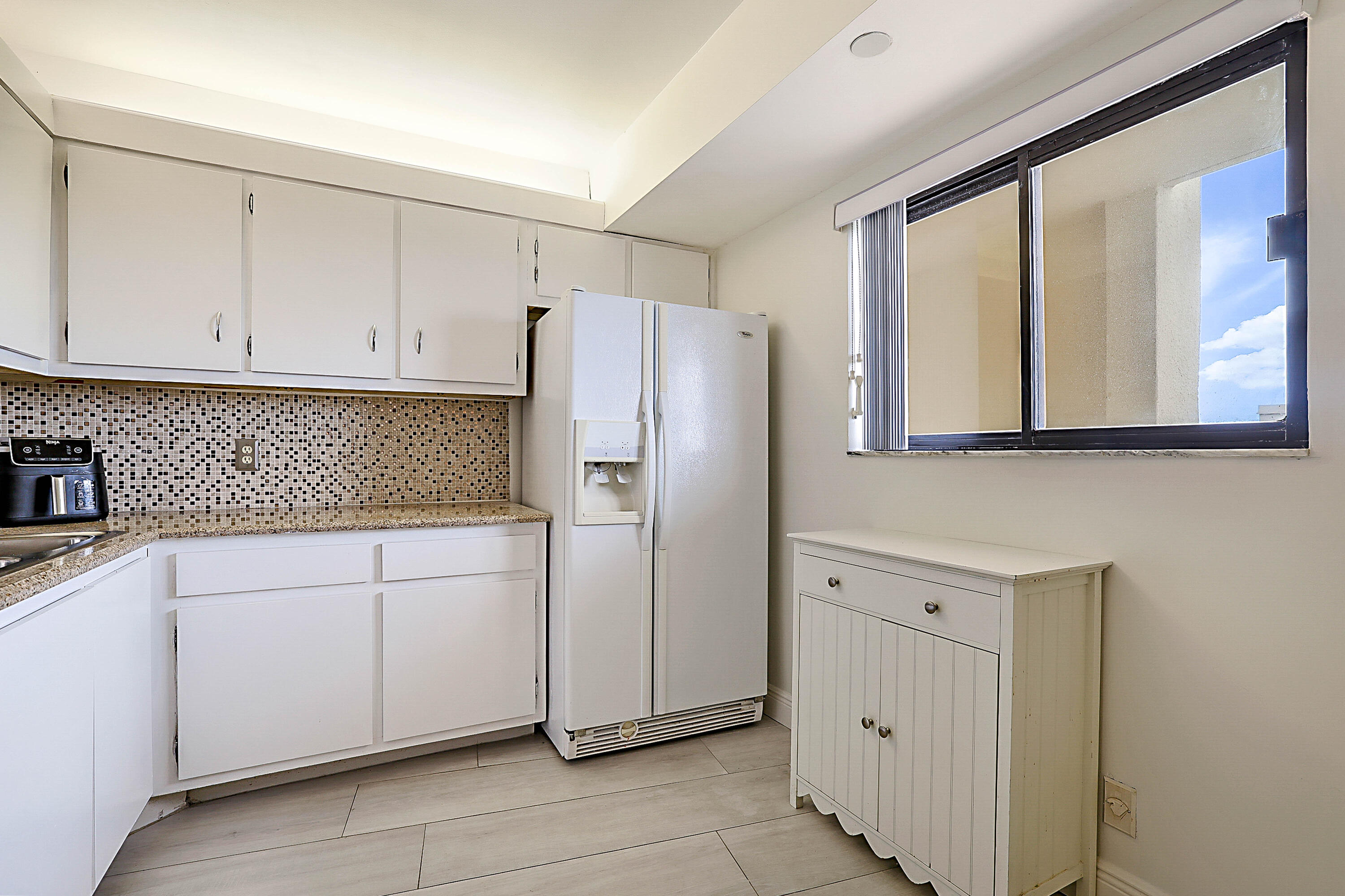 100 Ocean Trail Way, Unit 1003 Jupiter, FL 33477 - Photo 12 of 33 a kitchen with white cabinets and refrigerator