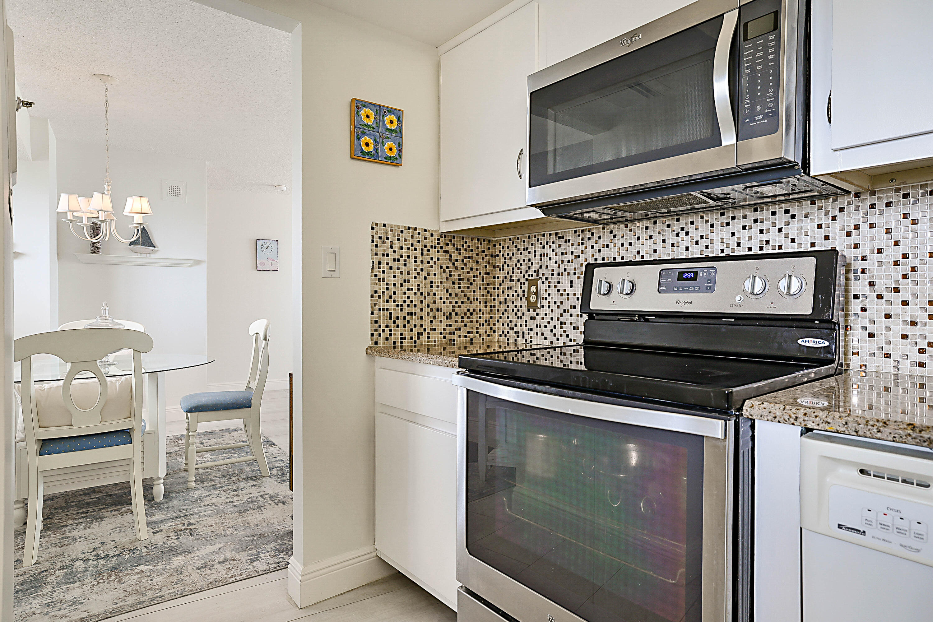 100 Ocean Trail Way, Unit 1003 Jupiter, FL 33477 - Photo 13 of 33 a kitchen with granite countertop a stove top oven microwave and cabinets