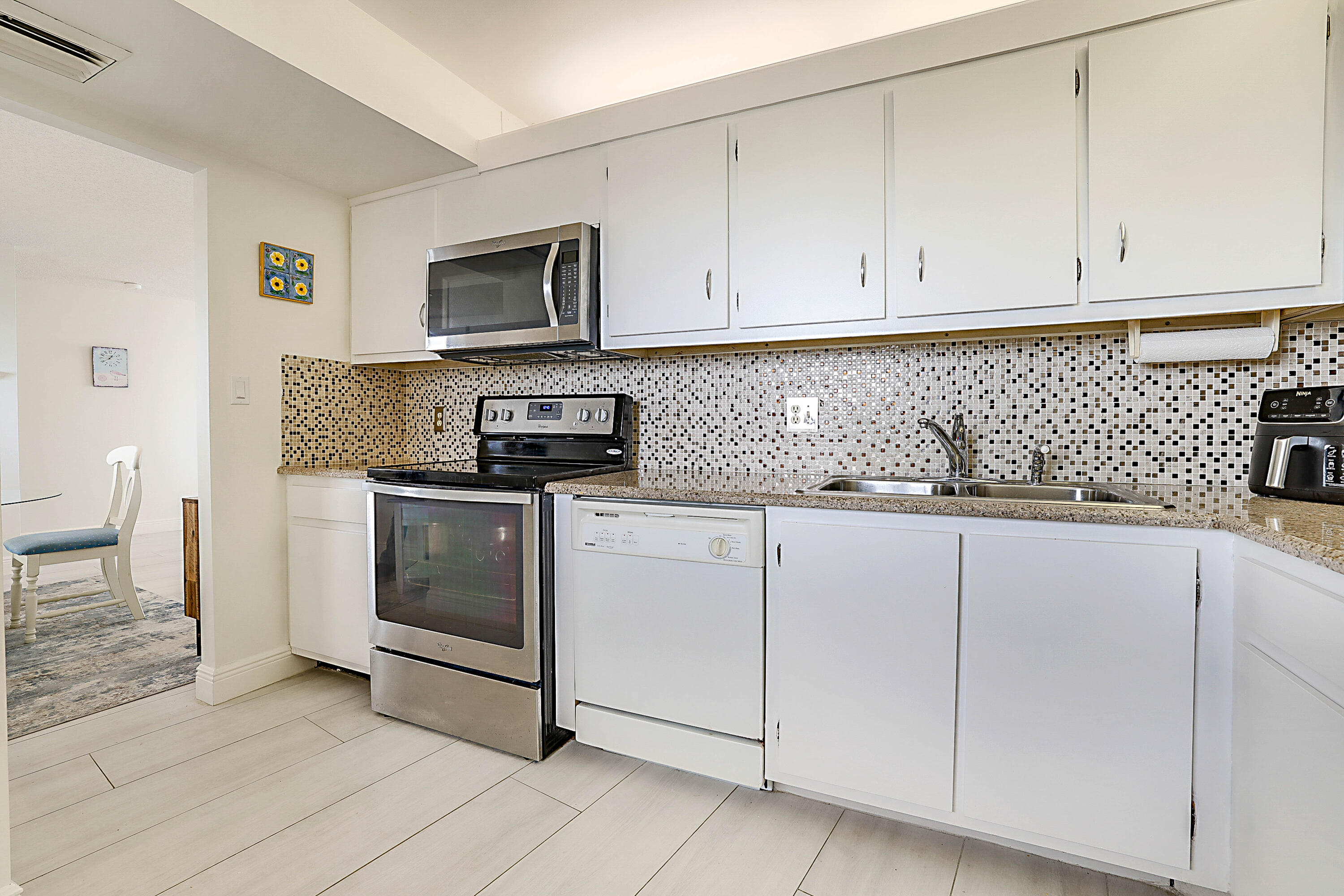 100 Ocean Trail Way, Unit 1003 Jupiter, FL 33477 - Photo 14 of 33 a kitchen with white cabinets and sink