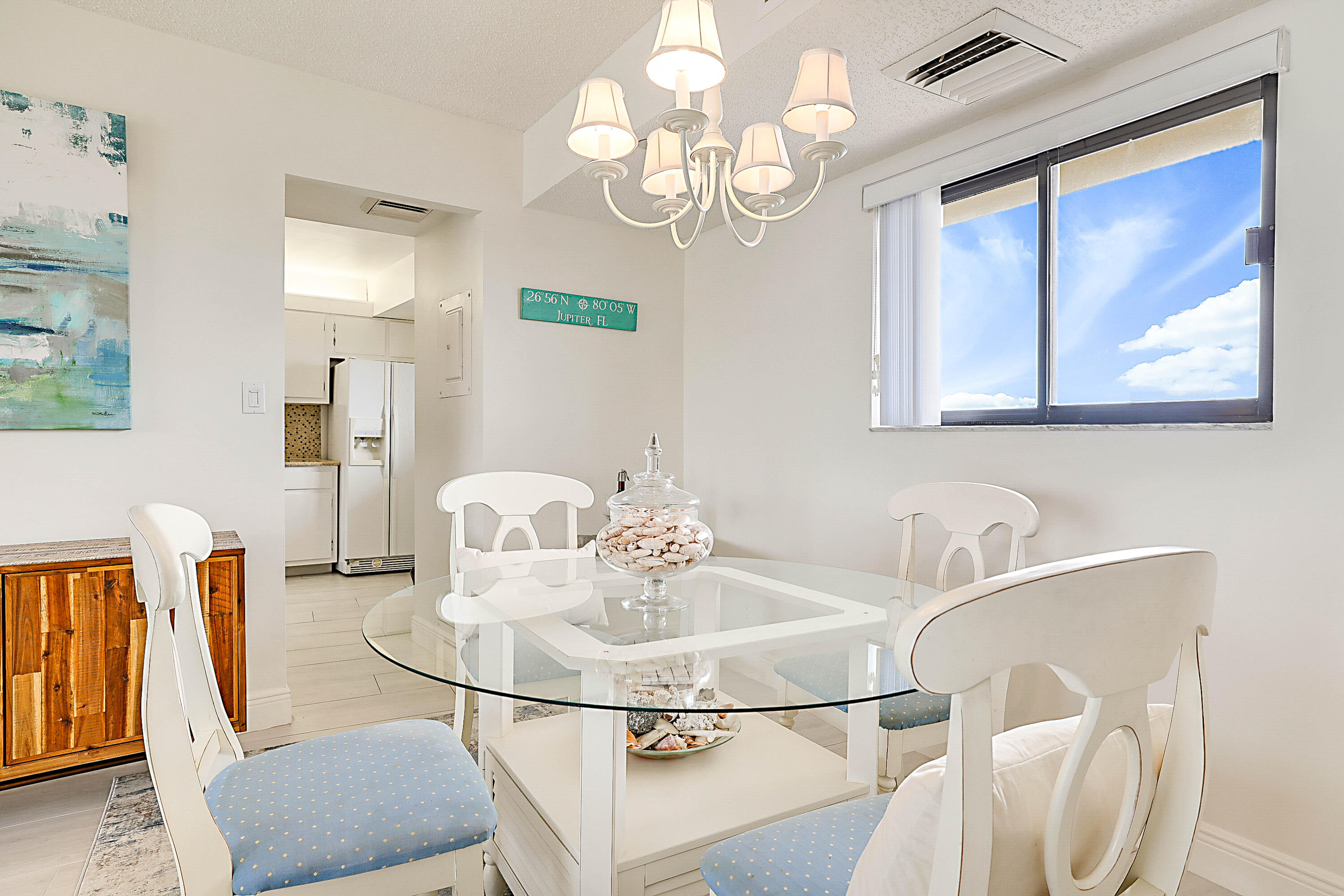 100 Ocean Trail Way, Unit 1003 Jupiter, FL 33477 - Photo 9 of 33 a dining room with wooden floor a chandelier a glass table and chairs