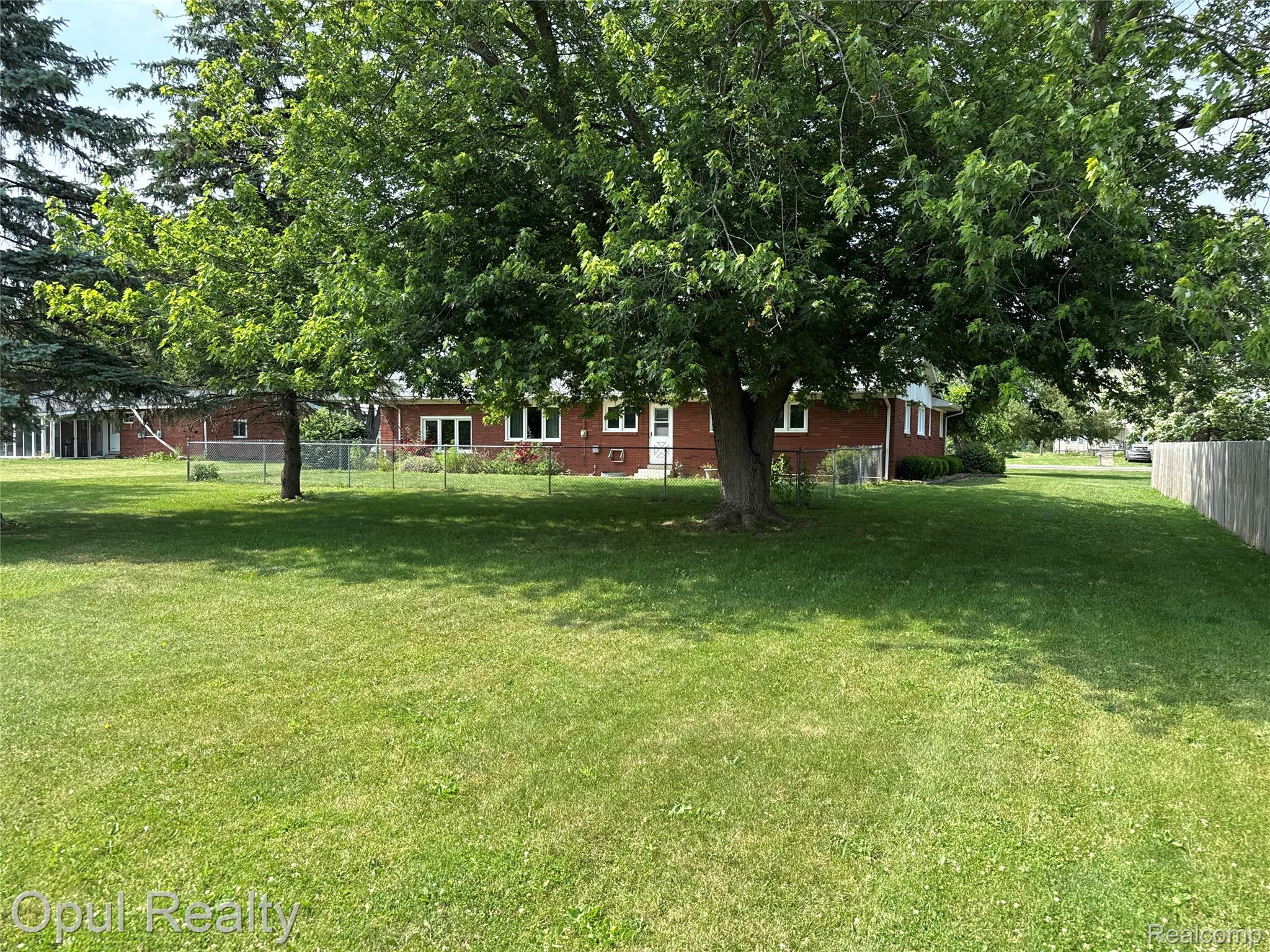 7899 Ida East Road Ida, MI 48140 - Photo 9 of 48 Spacious rear yard featuring a substantial mature tree providing natural shade, a partial chain-link fence, and a wooden privacy fence