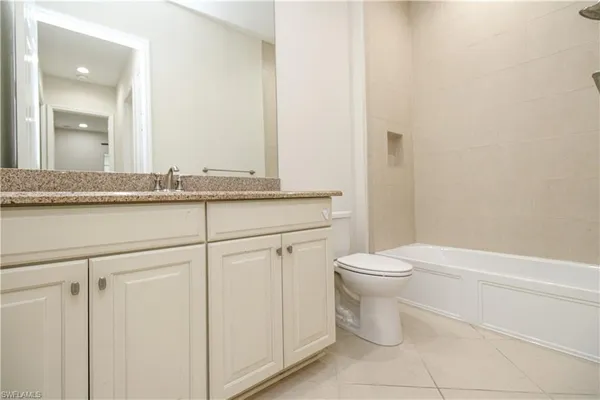 a bathroom with a granite countertop toilet and a sink