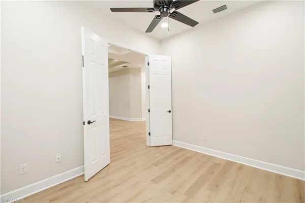 an empty room with wooden floor fan and windows