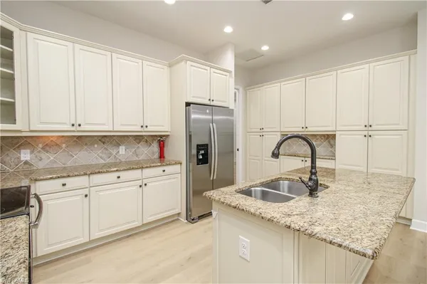 a kitchen with granite countertop white cabinets and refrigerator
