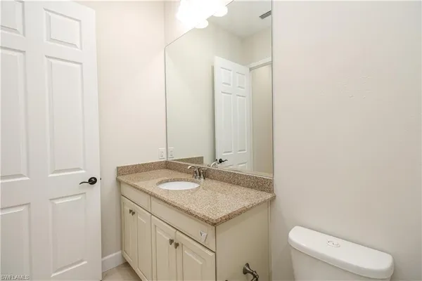 a bathroom with a granite countertop sink and a toilet