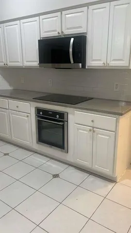 a kitchen with white cabinets and stainless steel appliances