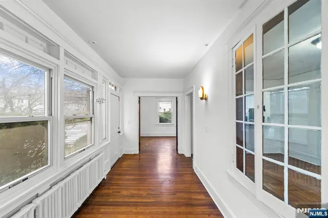 a view of a hallway with wooden floor and windows