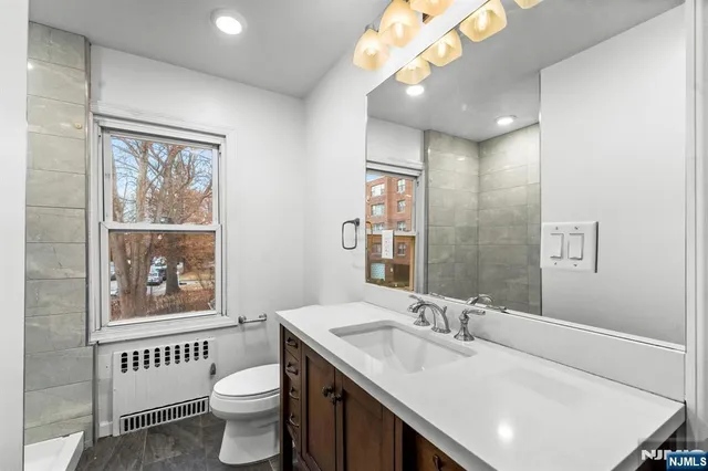 a bathroom with a sink a mirror a toilet and a window