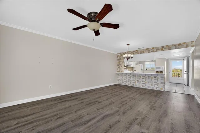 a view of an empty room with wooden floor and a ceiling fan