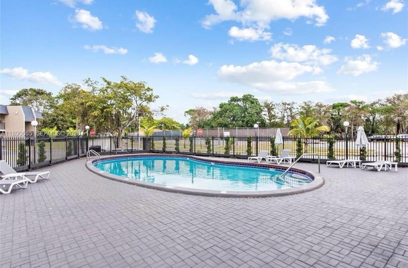 8060 North Colony Circle, Unit 207 Tamarac, FL 33321 - Photo 13 of 14 a view of a swimming pool with an outdoor seating and a garden