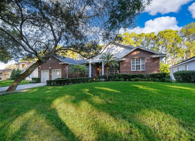 a view of a house with a big yard plants and large trees