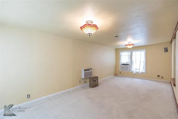 an empty room with windows and chandelier fan