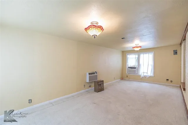 an empty room with windows and chandelier fan