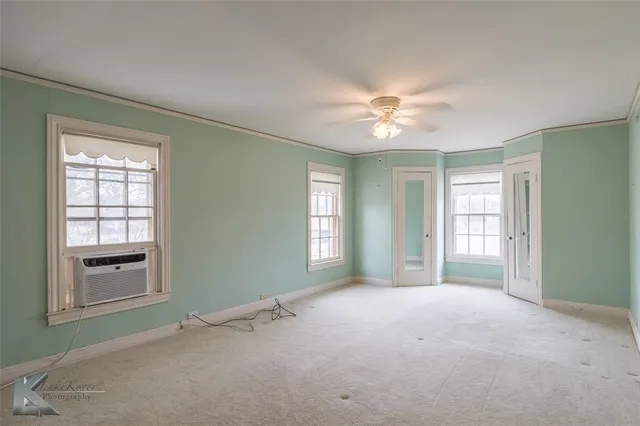 a view of an empty room with a window and a kitchen