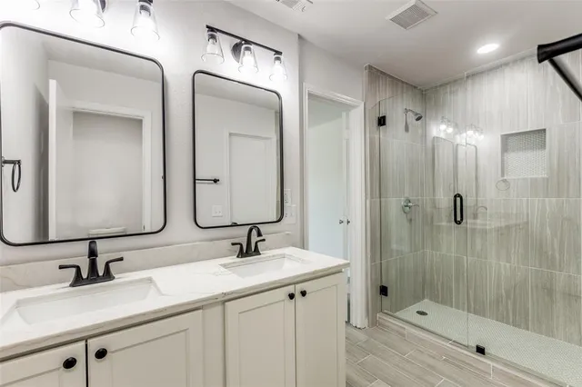 a bathroom with a double vanity sink mirror and shower