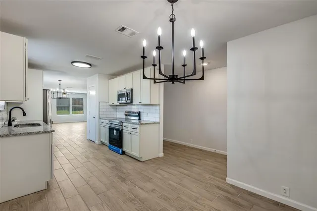 a large kitchen with stainless steel appliances granite countertop a sink a stove and a wooden floors