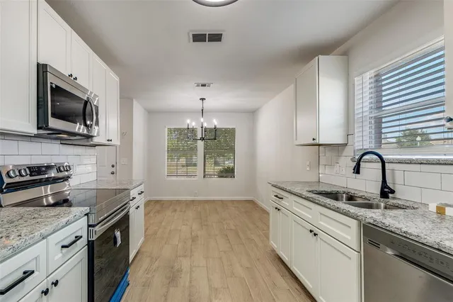 a kitchen with granite countertop stainless steel appliances a sink stove top oven and cabinets