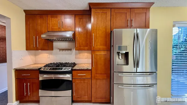a kitchen with stainless steel appliances granite countertop a refrigerator stove and sink
