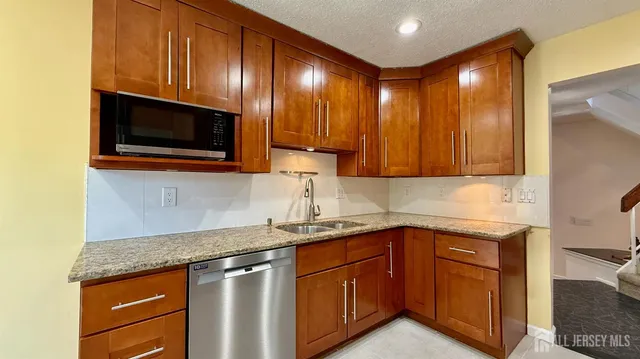 a kitchen with stainless steel appliances granite countertop wooden cabinets a sink and dishwasher