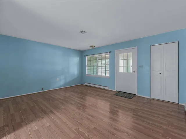 a view of an empty room with wooden floor and a window
