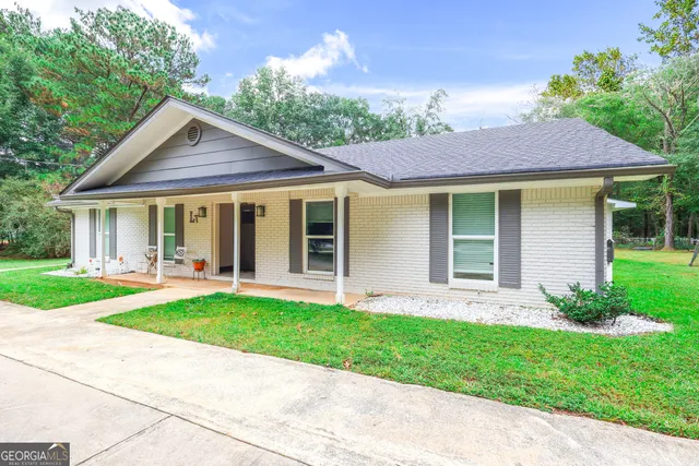 a front view of a house with a yard and potted plants