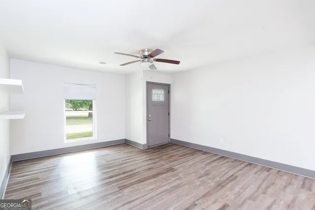 an empty room with wooden floor and windows