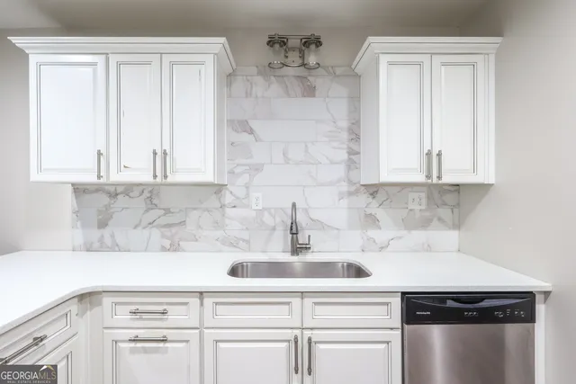 a kitchen with white cabinets and sink