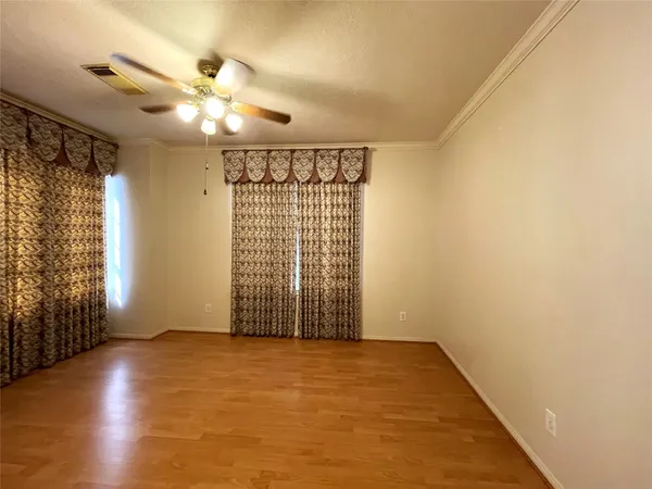 an empty room with wooden floor fan and windows