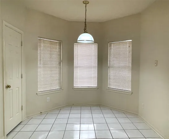 an empty room with windows and chandelier fan
