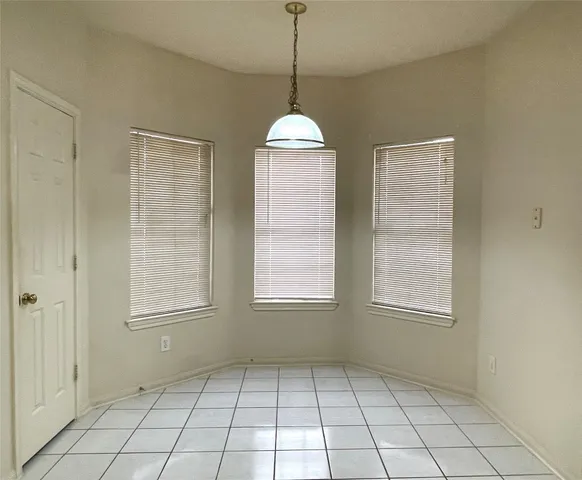 an empty room with windows and chandelier fan