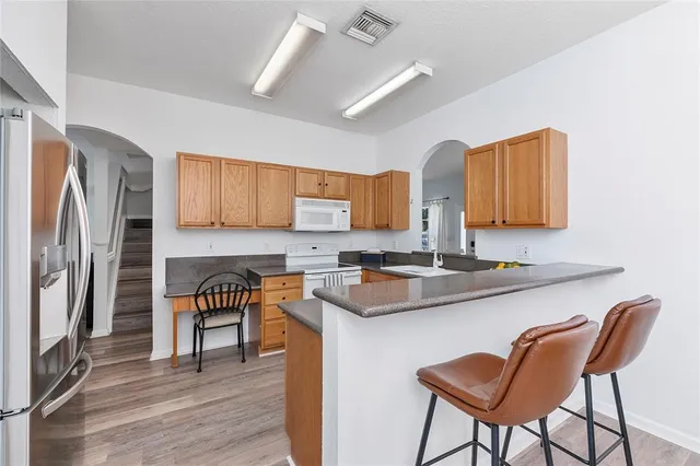 a kitchen with stainless steel appliances granite countertop a table chairs in it and wooden floors