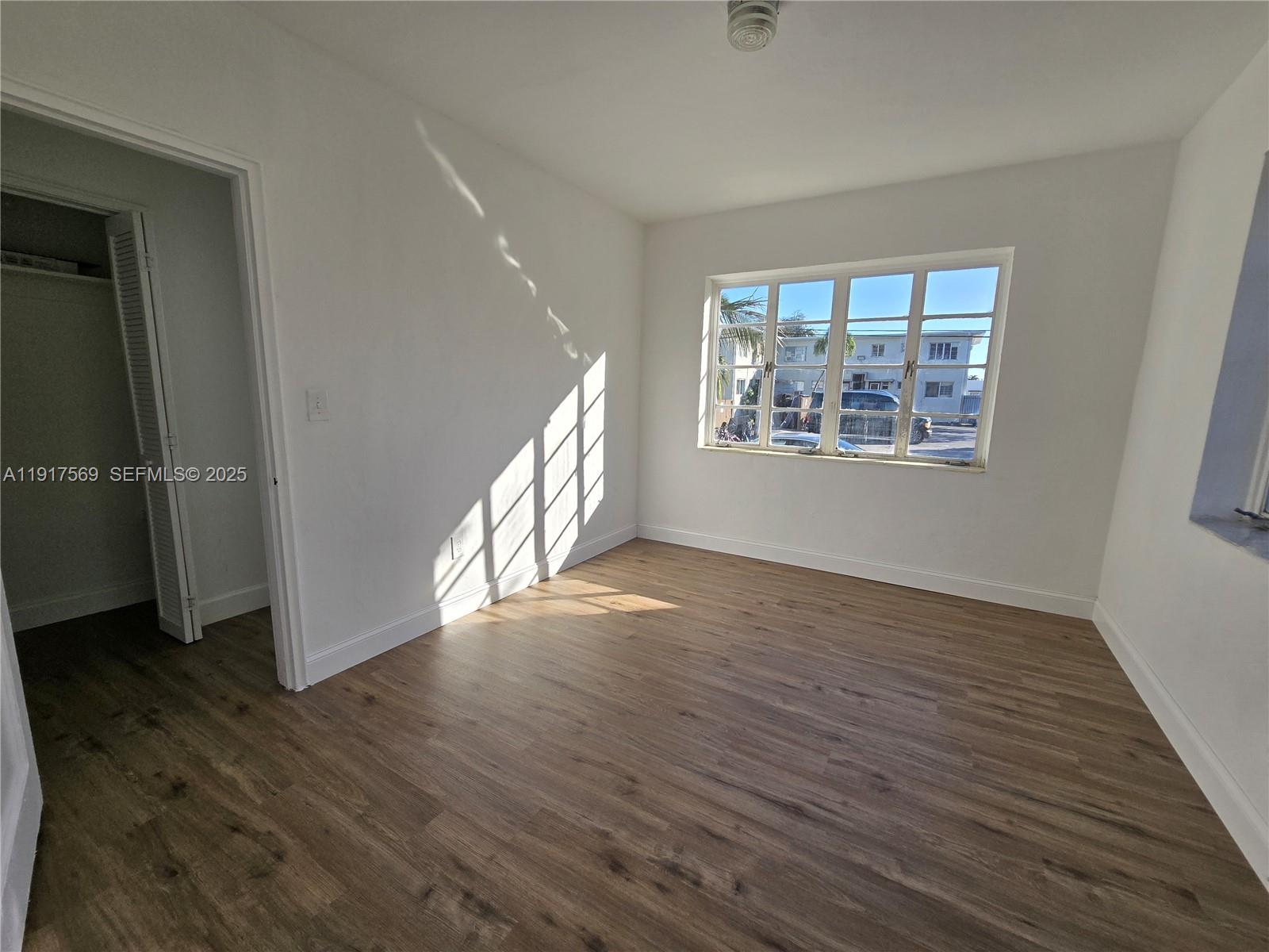 660 84th Street, Unit 39 Miami Beach, FL 33141 - Photo 12 of 17 an empty room with wooden floor and windows