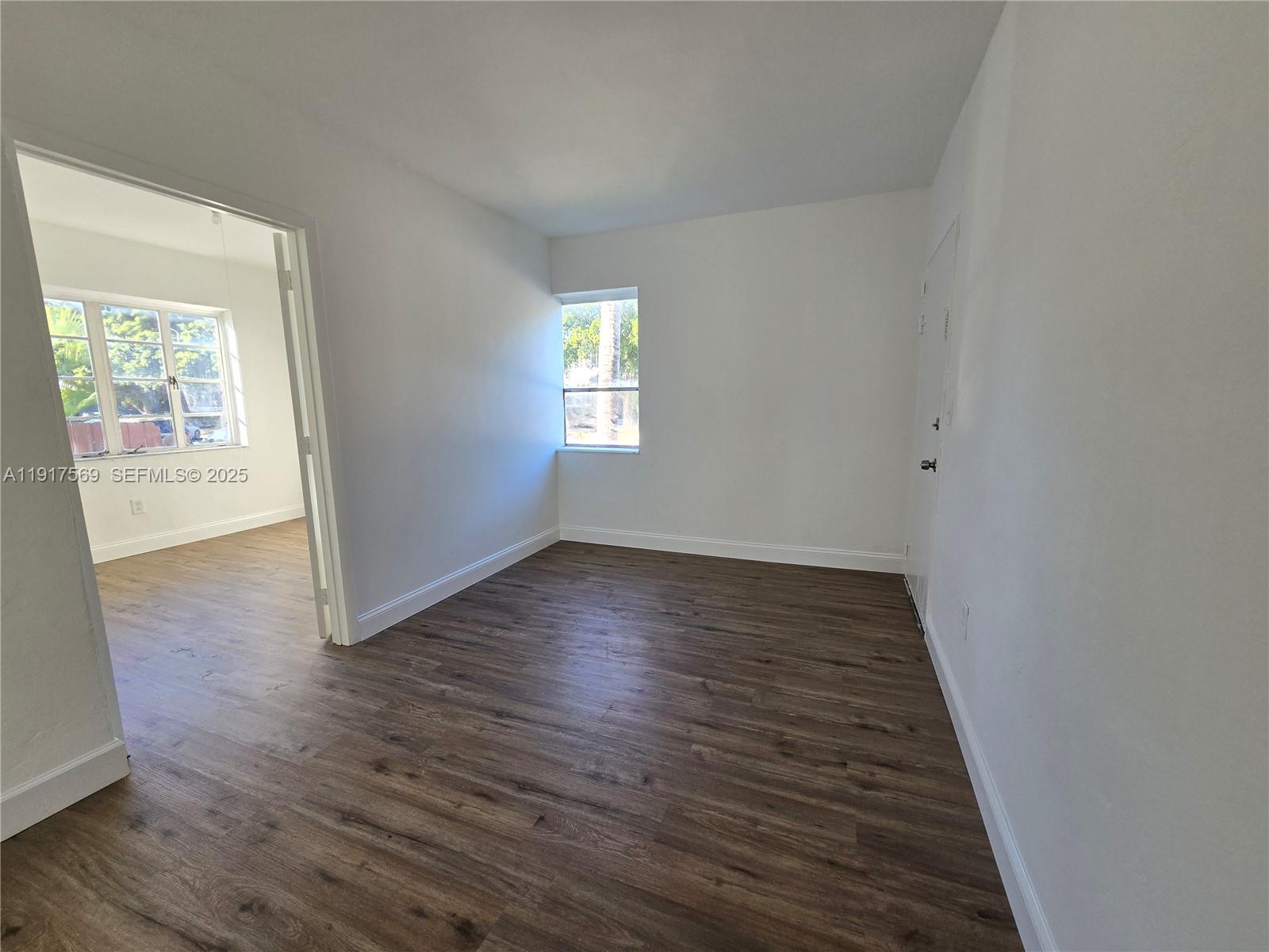 660 84th Street, Unit 39 Miami Beach, FL 33141 - Photo 5 of 17 an empty room with wooden floor and windows
