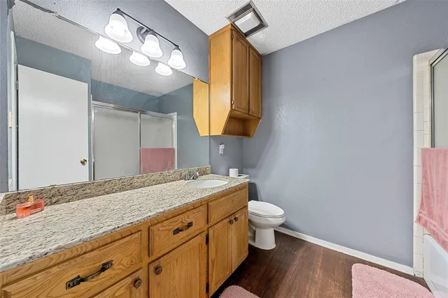 a bathroom with a granite countertop sink a toilet and a mirror