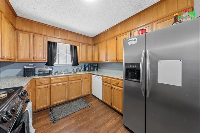 a kitchen with stainless steel appliances granite countertop a refrigerator a sink dishwasher with a cabinets and wooden floor