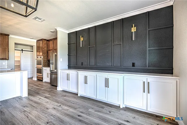 a kitchen with stainless steel appliances wooden cabinets and a view of living room