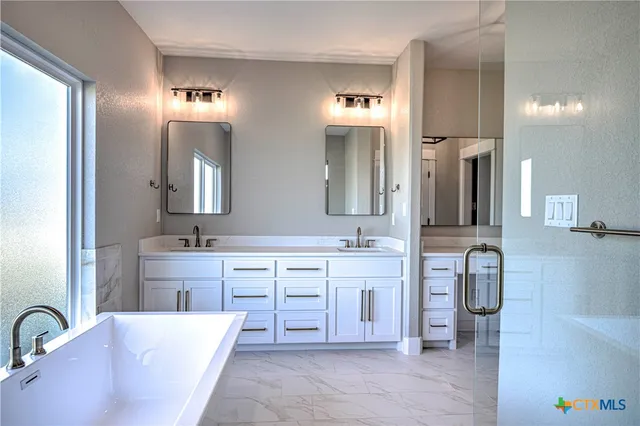 a spacious bathroom with a double vanity sink mirror and bathtub