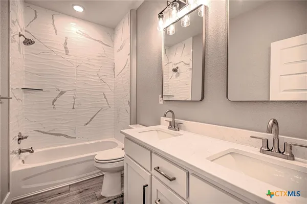 a bathroom with a granite countertop sink a toilet and bathtub