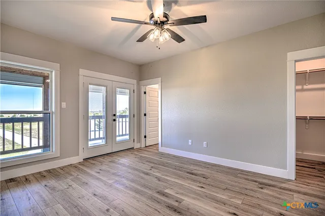 a view of an empty room with window and wooden floor