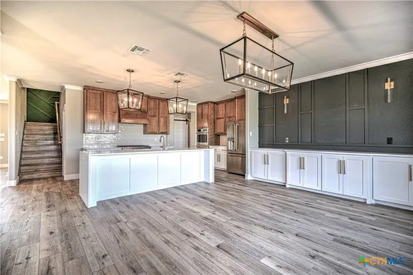 a large kitchen with cabinets wooden floor and stainless steel appliances