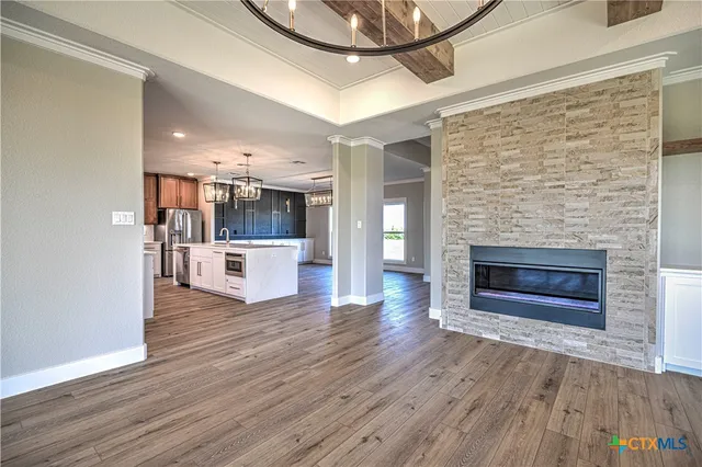 a living room with stainless steel appliances furniture a fireplace and wooden floor