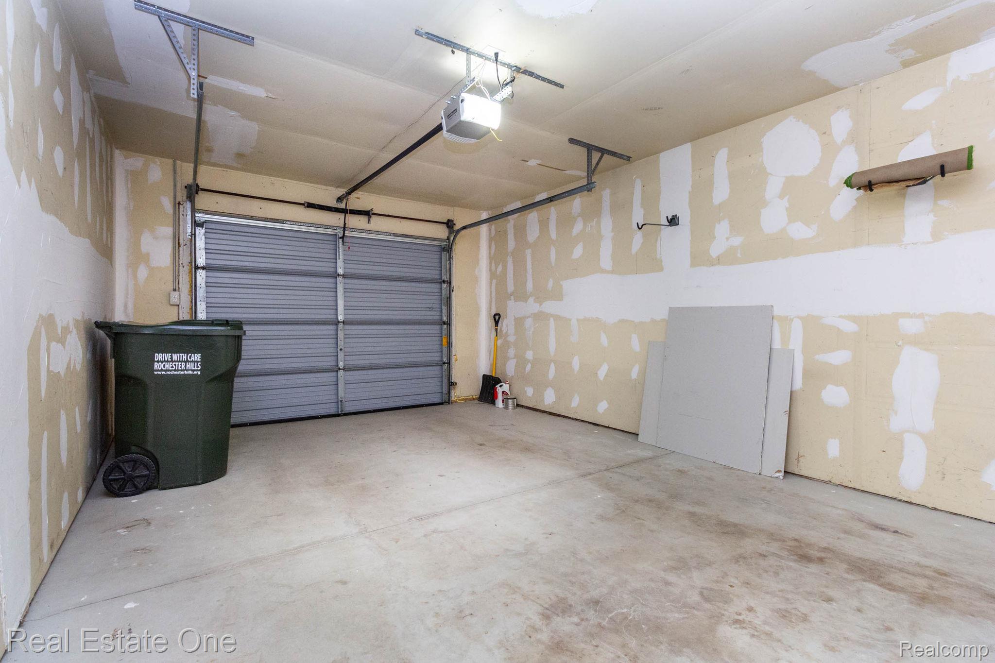 111 Manor Way Rochester, MI 48309 - Photo 26 of 36 Spacious garage with a roll-up door, exposed ceiling joists, and concrete flooring