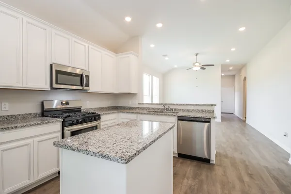 a kitchen with stainless steel appliances granite countertop a sink stove and microwave