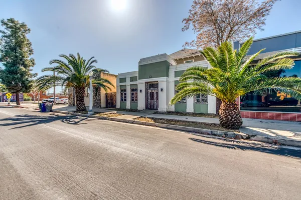 a view of a street with a building and palm trees