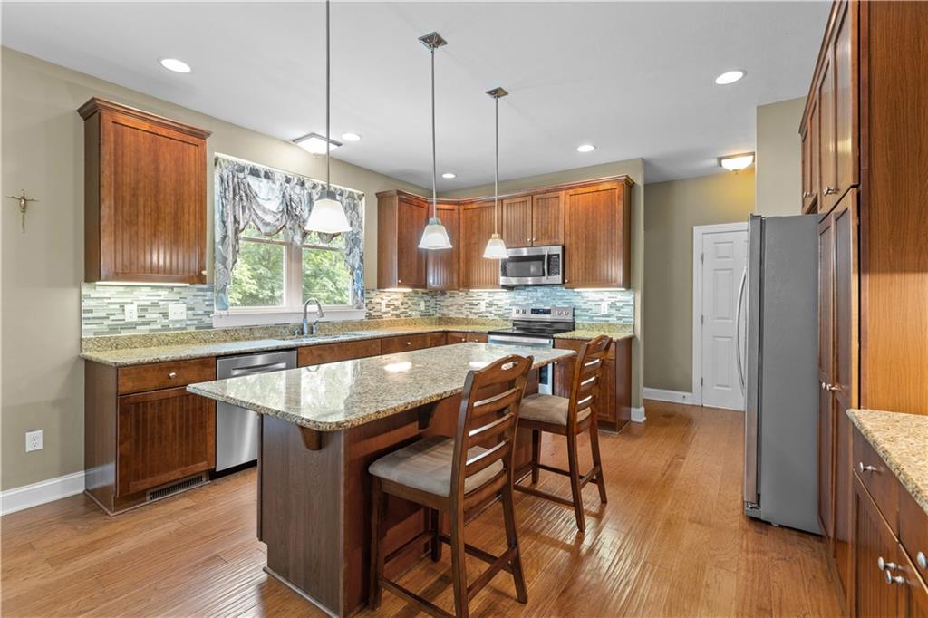 242 Kings Road Washington, PA 15301 - Photo 16 of 42 a kitchen with granite countertop wooden floors cabinets a dining table and appliances