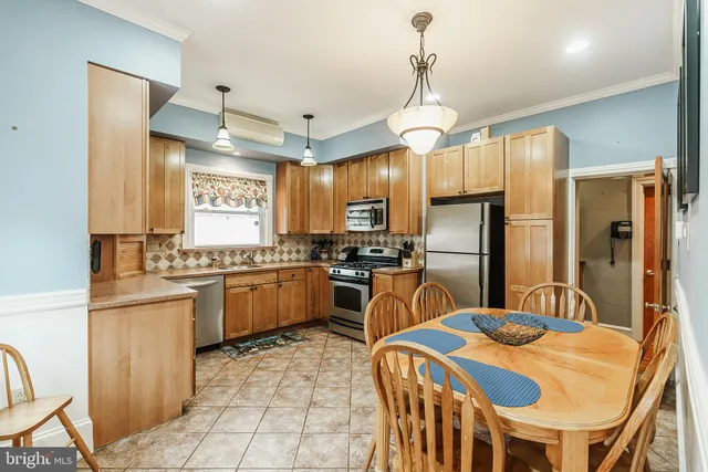 a kitchen with stainless steel appliances granite countertop a sink a stove a refrigerator cabinets and chairs