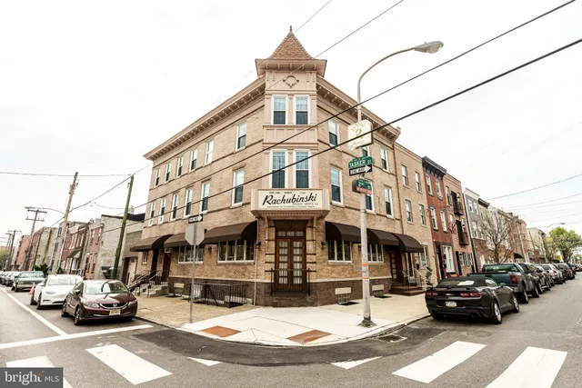 a front view of a building with cars parked