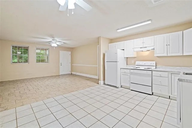 a kitchen with a stove a refrigerator and white cabinets