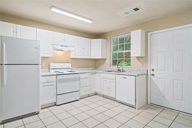 a kitchen with granite countertop white cabinets and white appliances